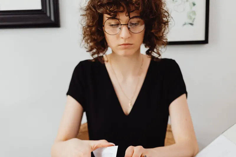 Administratief medewerker met bril ordent papieren aan haar bureau