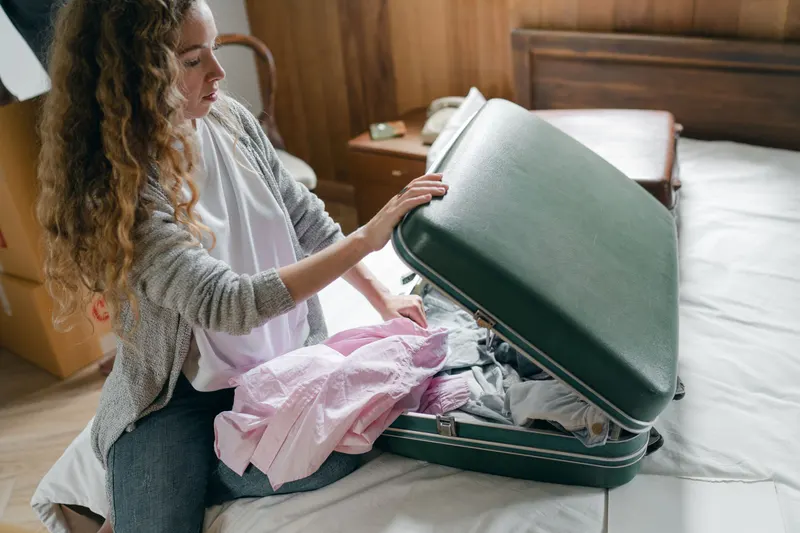 Vrouw pakt kleding in een koffer op bed, klaar voor vakantie van haar vakantiegeld