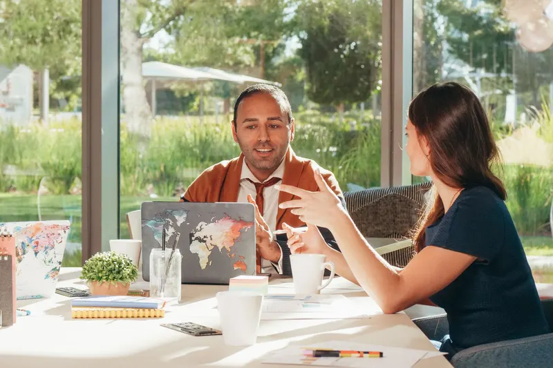 Man en vrouw voeren een ontspannen kennismakingsgesprek aan tafel, zonder cv op papier