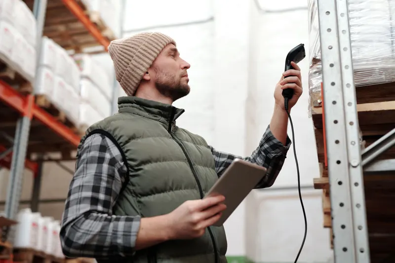Orderpicker scant met een handscanner producten in een magazijnstelling