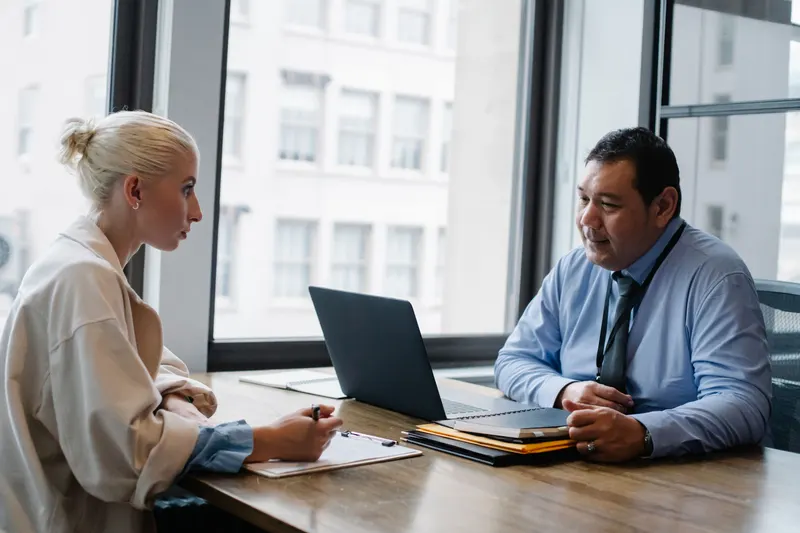 Zakelijk sollicitatiegesprek aan een bureau met laptop tussen een kandidaat en een recruiter