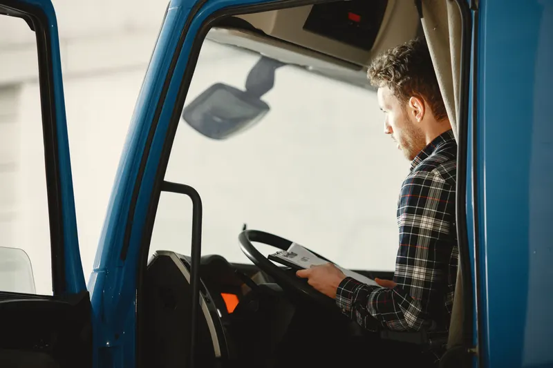 Vrachtwagenchauffeur in de cabine bekijkt de vrachtpapieren op een klembord