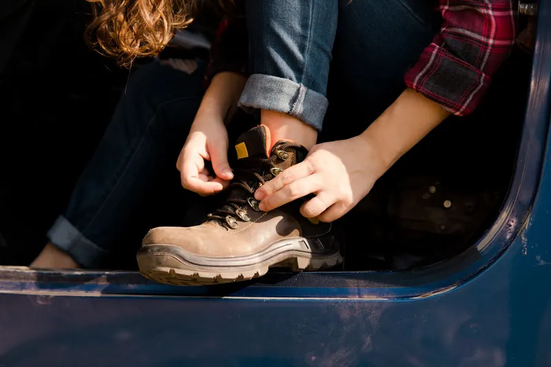 Iemand strikt de veters van stevige werkschoenen, klaar voor de eerste werkdag